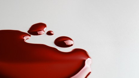 Photo of Stain and drops of blood on light grey background, closeup. Space for text