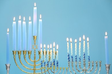 Photo of Hanukkah celebration. Menorahs with burning candles on light blue background