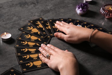 Photo of Soothsayer predicting future with tarot cards at table, closeup