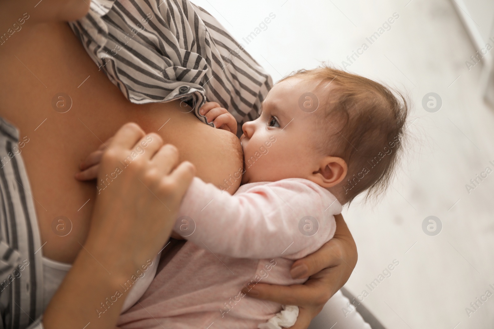 Photo of Young woman breastfeeding her baby at home, closeup