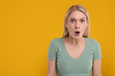 Portrait of surprised woman on yellow background, space for text