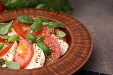 Photo of Plate of delicious Caprese salad with pesto sauce on brown textured table, closeup. Space for text