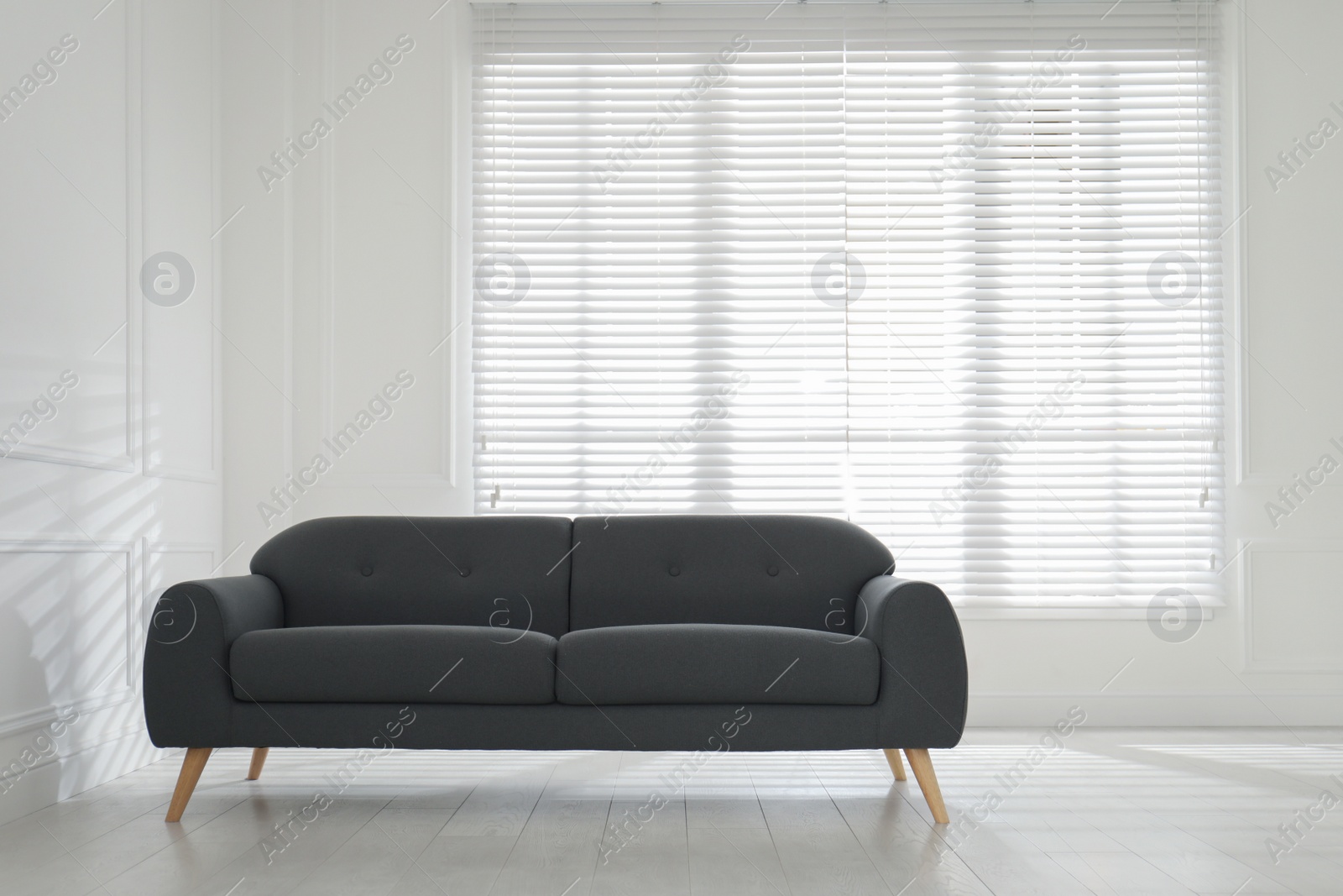 Photo of Comfortable grey sofa near window indoors. Interior design