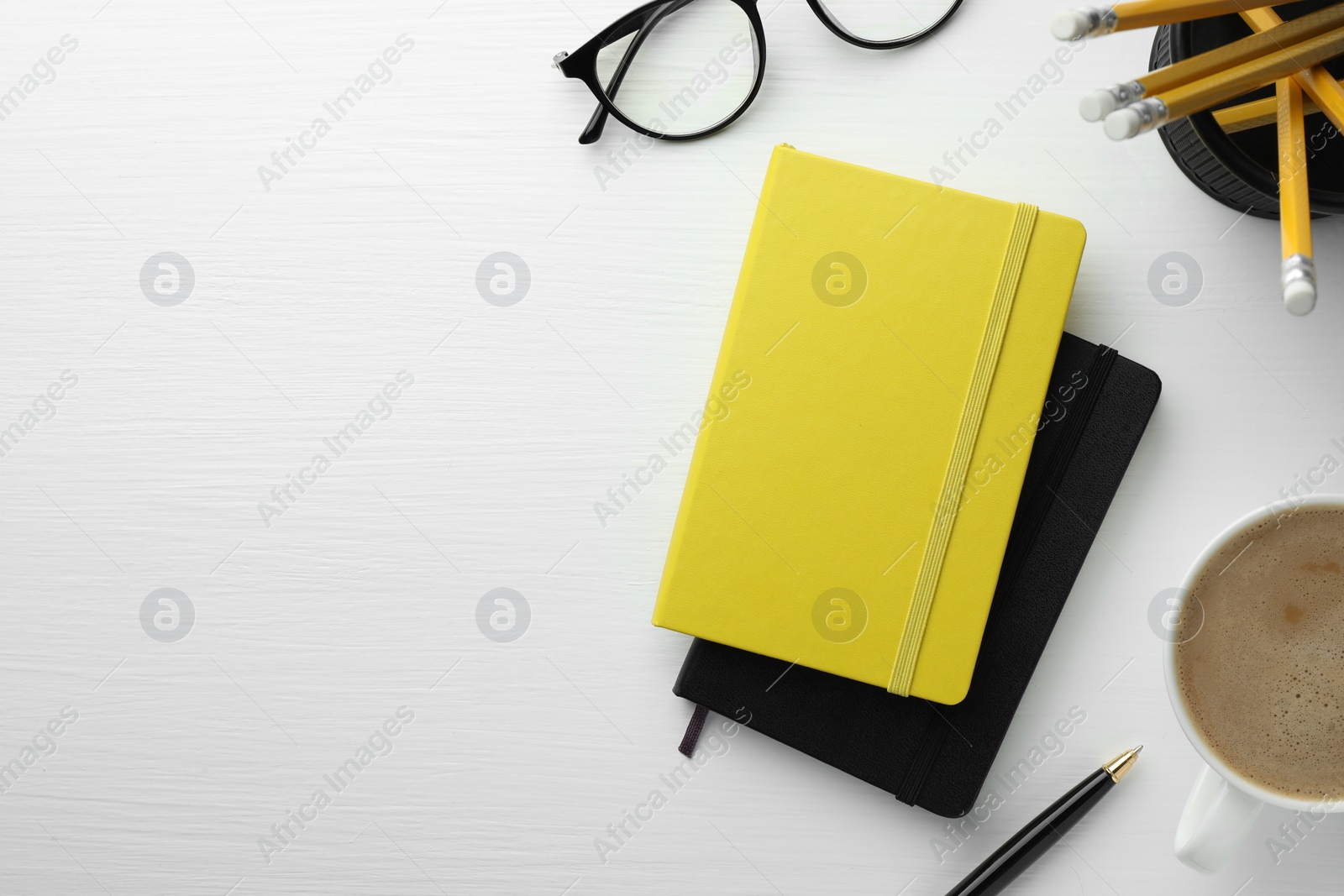 Photo of Different notebooks, cup of coffee, glasses and stationery on white wooden table, flat lay. Space for text