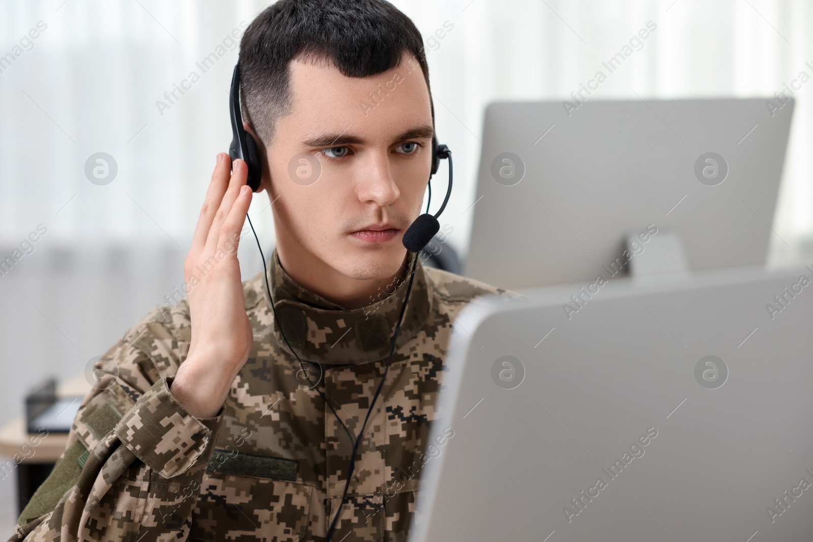 Photo of Military service. Young soldier in headphones working in office