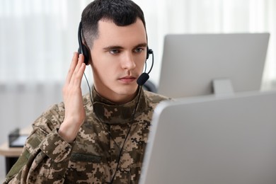 Photo of Military service. Young soldier in headphones working in office