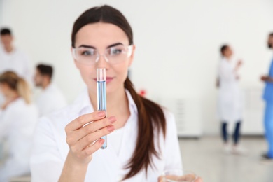 Medical student with test tube in laboratory. Space for text