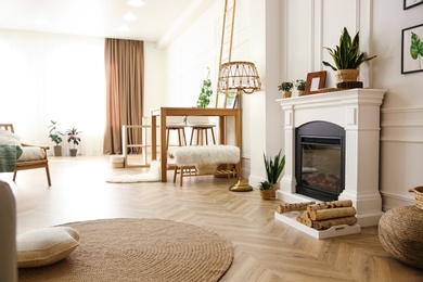 Photo of Elegant artificial fireplace and wooden table in room. Interior design