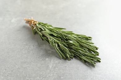 Photo of Fresh rosemary twigs tied with twine on gray table, closeup