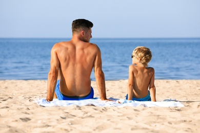 Father and son on sandy beach near sea. Summer holidays with family
