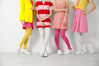 Women wearing colorful tights near white wall, closeup