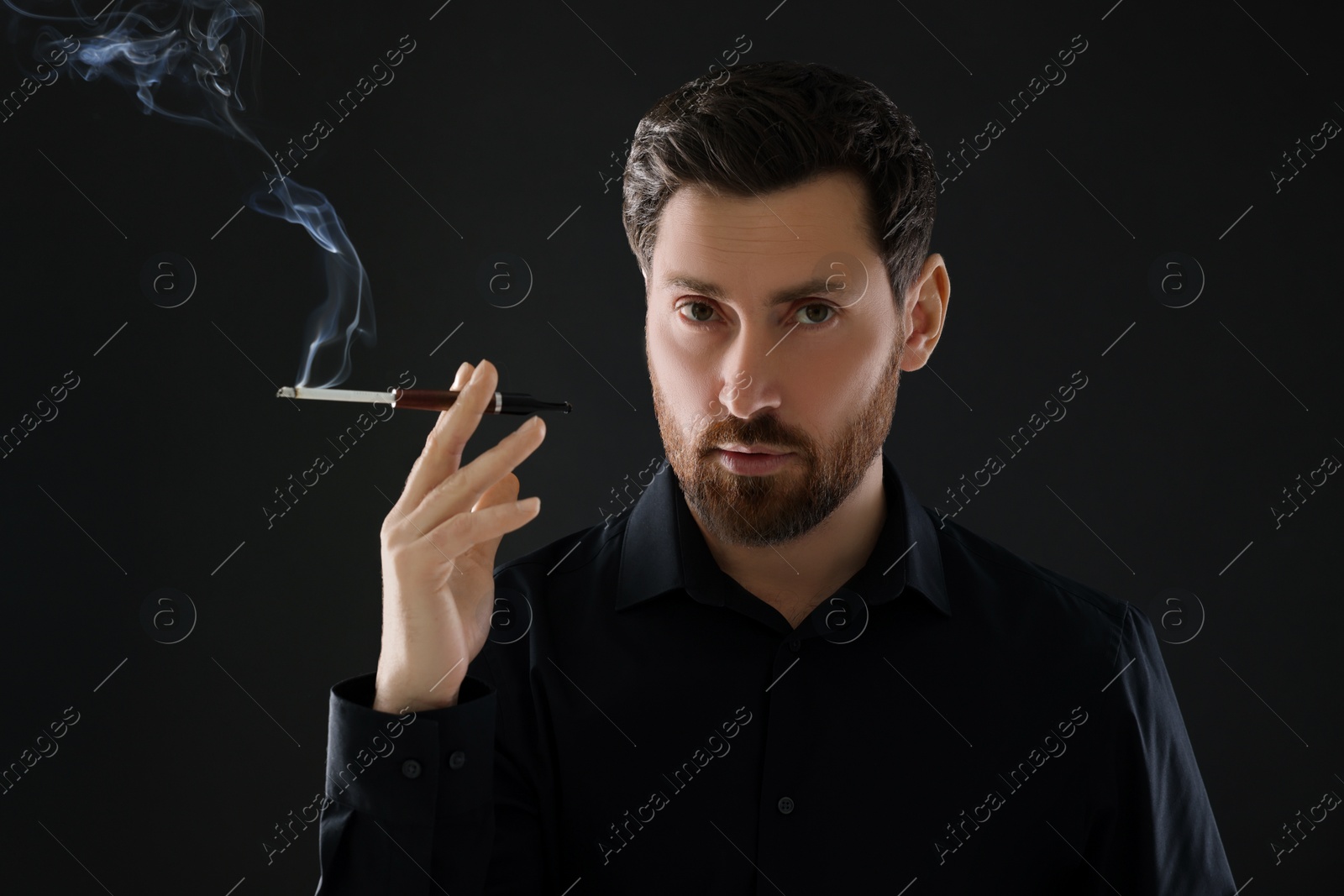 Photo of Man using cigarette holder for smoking on black background