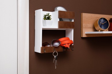 Photo of Stylish hanger for keys on brown wall in hallway