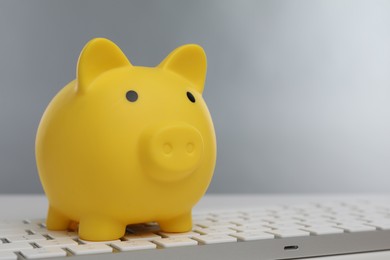 Photo of Yellow piggy bank and keyboard on white table, space for text