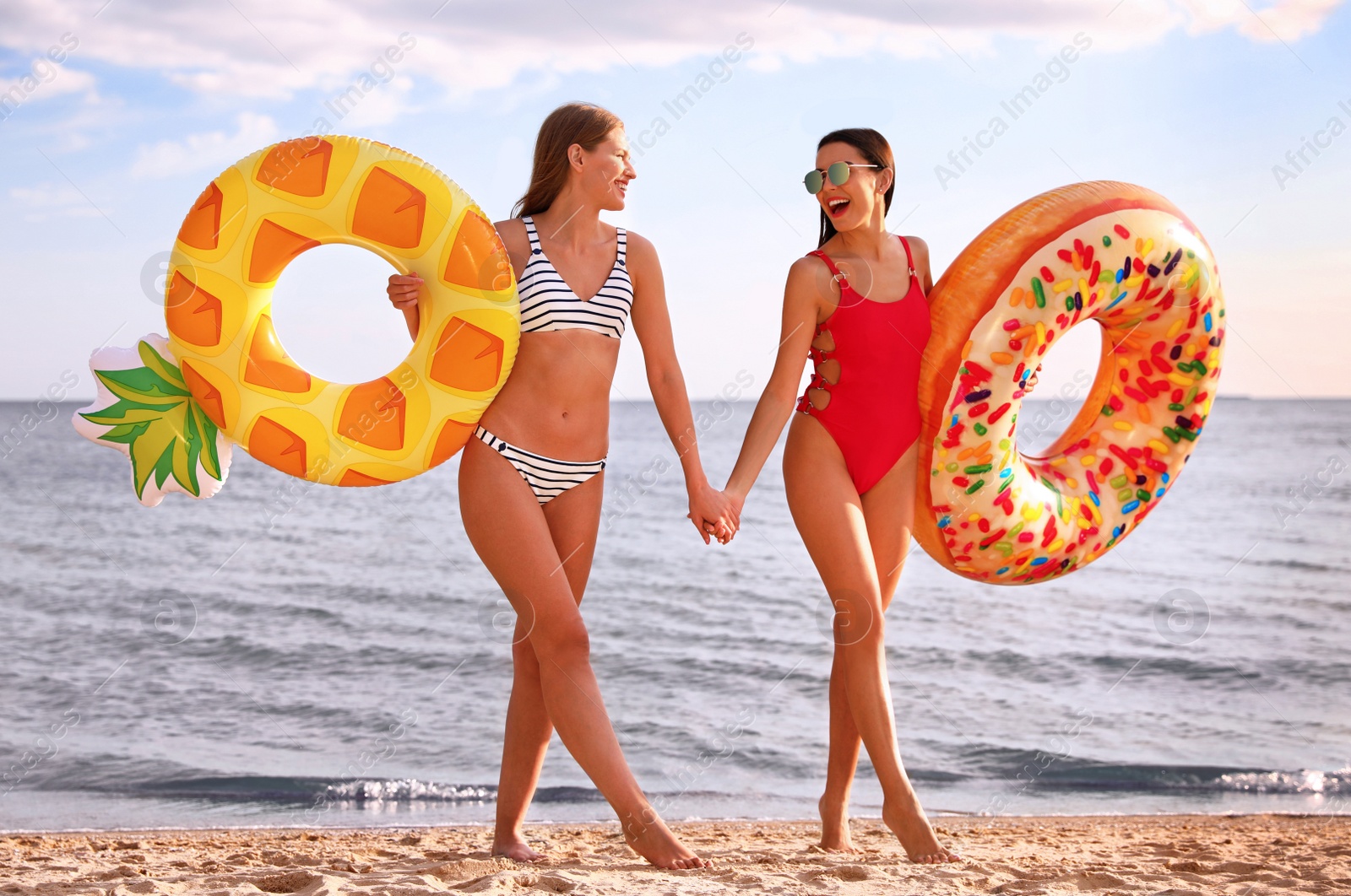 Photo of Young woman in bikini with girlfriend on beach. Lovely couple