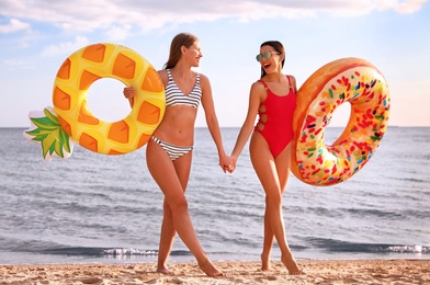 Young woman in bikini with girlfriend on beach. Lovely couple