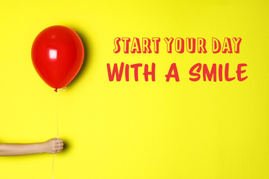 Image of Change your life. Inspirational text Start Your Day With A Smile and woman holding red balloon on yellow background