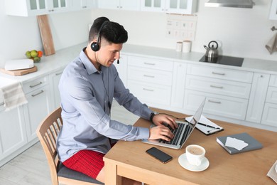 Photo of Businessman in shirt and underwear working on laptop at home