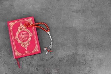 Muslim prayer beads, Quran and space for text on grey background, top view