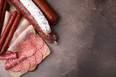 Photo of Different types of sausages on brown table, flat lay. Space for text