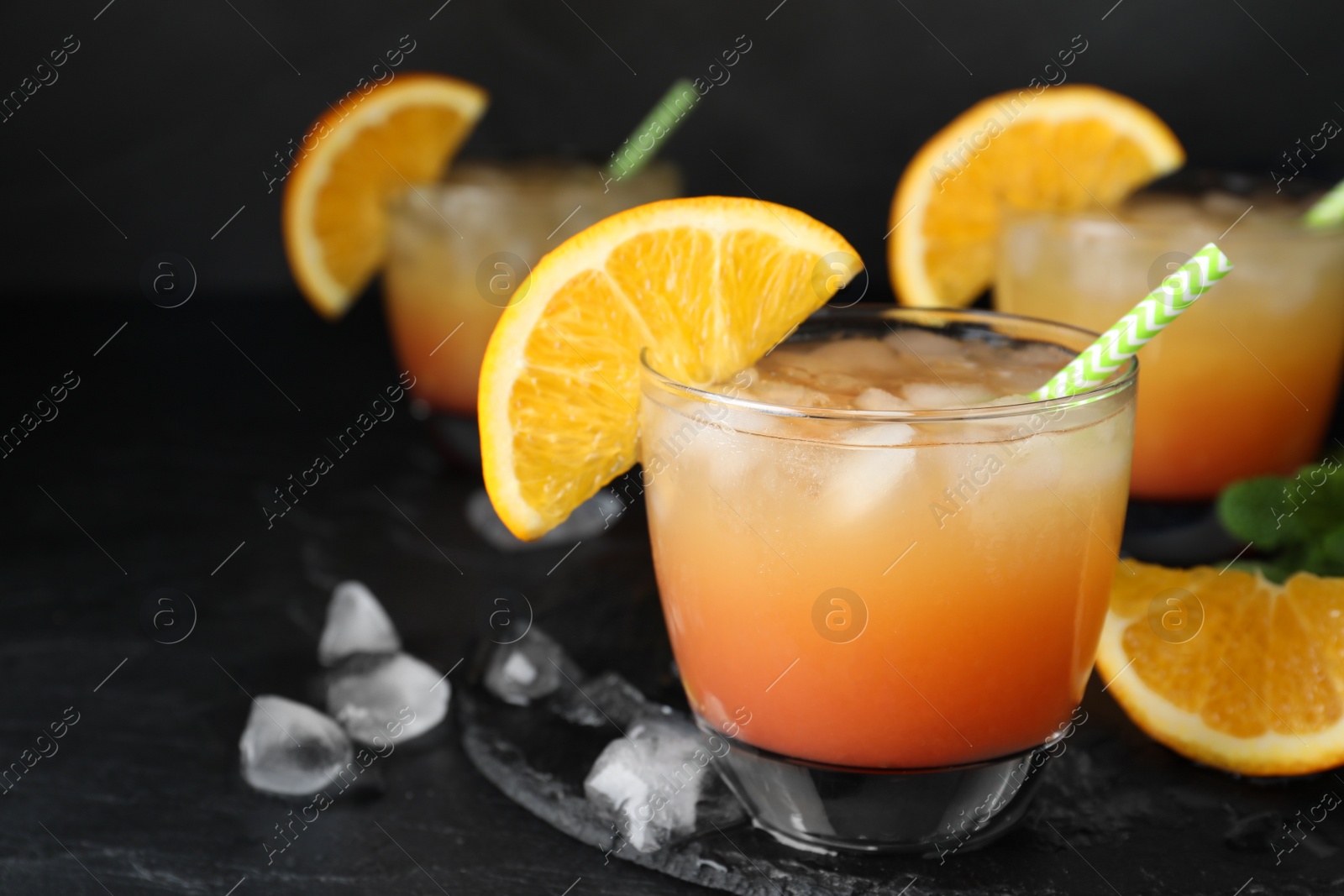 Photo of Glass of tasty tropical cocktail on black table