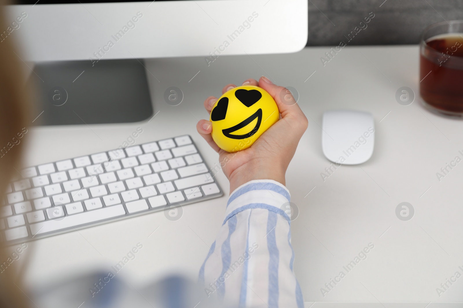 Photo of Woman squeezing antistress ball at workplace, closeup