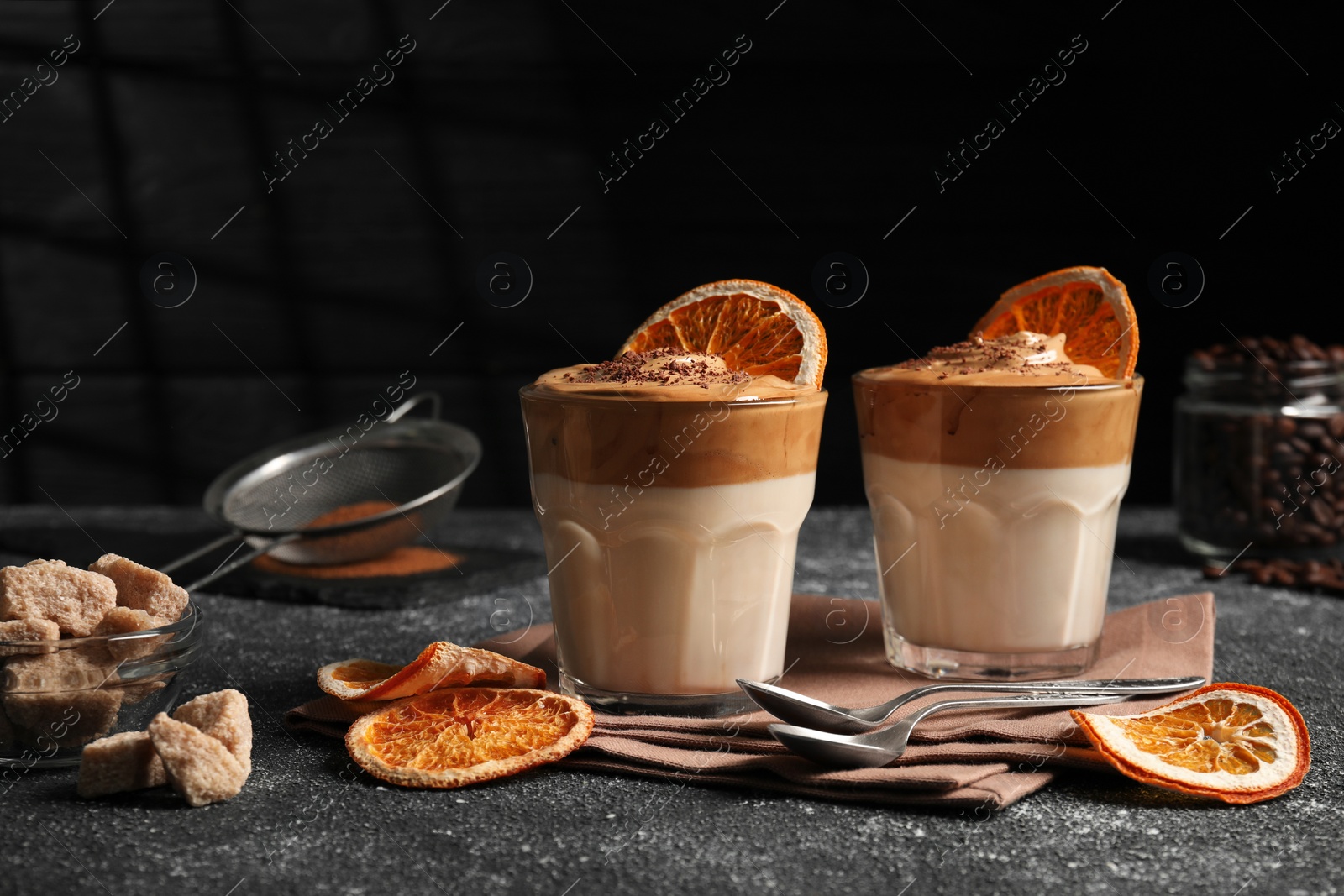 Photo of Glasses of delicious dalgona coffee with ingredients on grey textured table