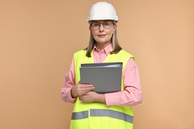 Photo of Architect in hard hat with folder on beige background