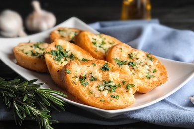 Plate with delicious homemade garlic bread on table