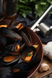 Plate of cooked mussels with parsley and garlic on table, closeup