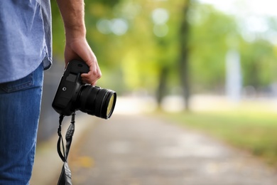 Photographer with professional camera in park, closeup