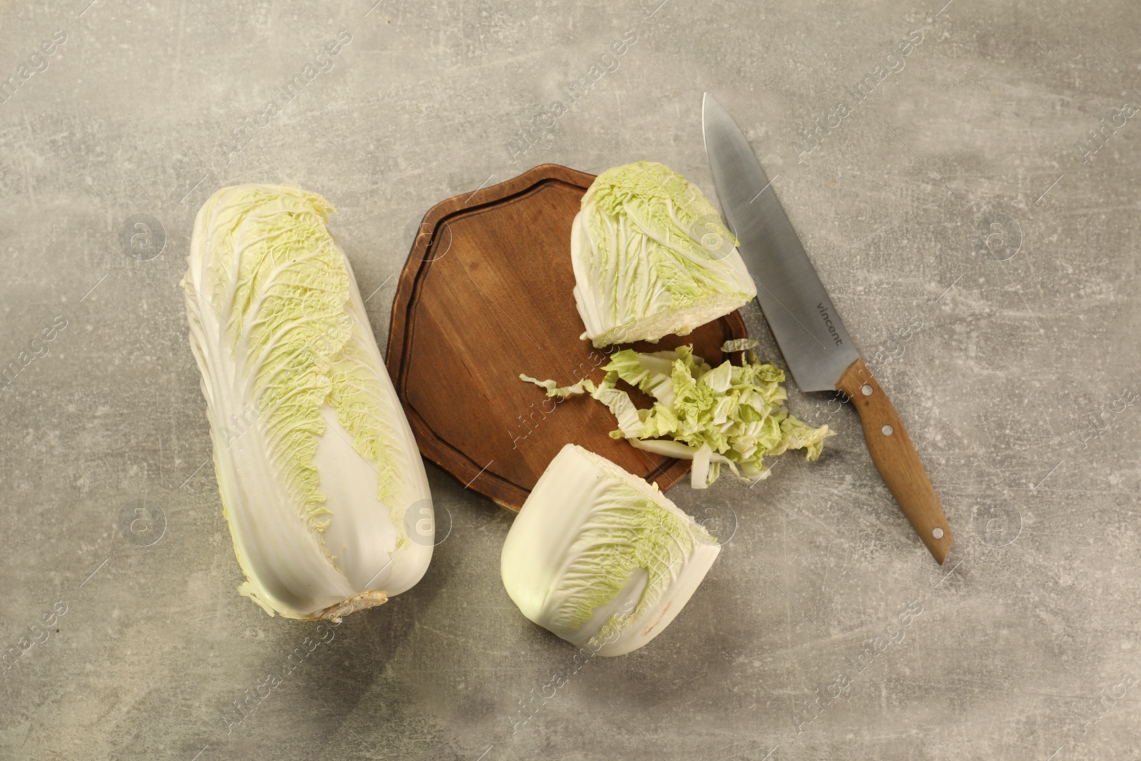 Photo of Whole and cut fresh Chinese cabbages on light grey table, flat lay