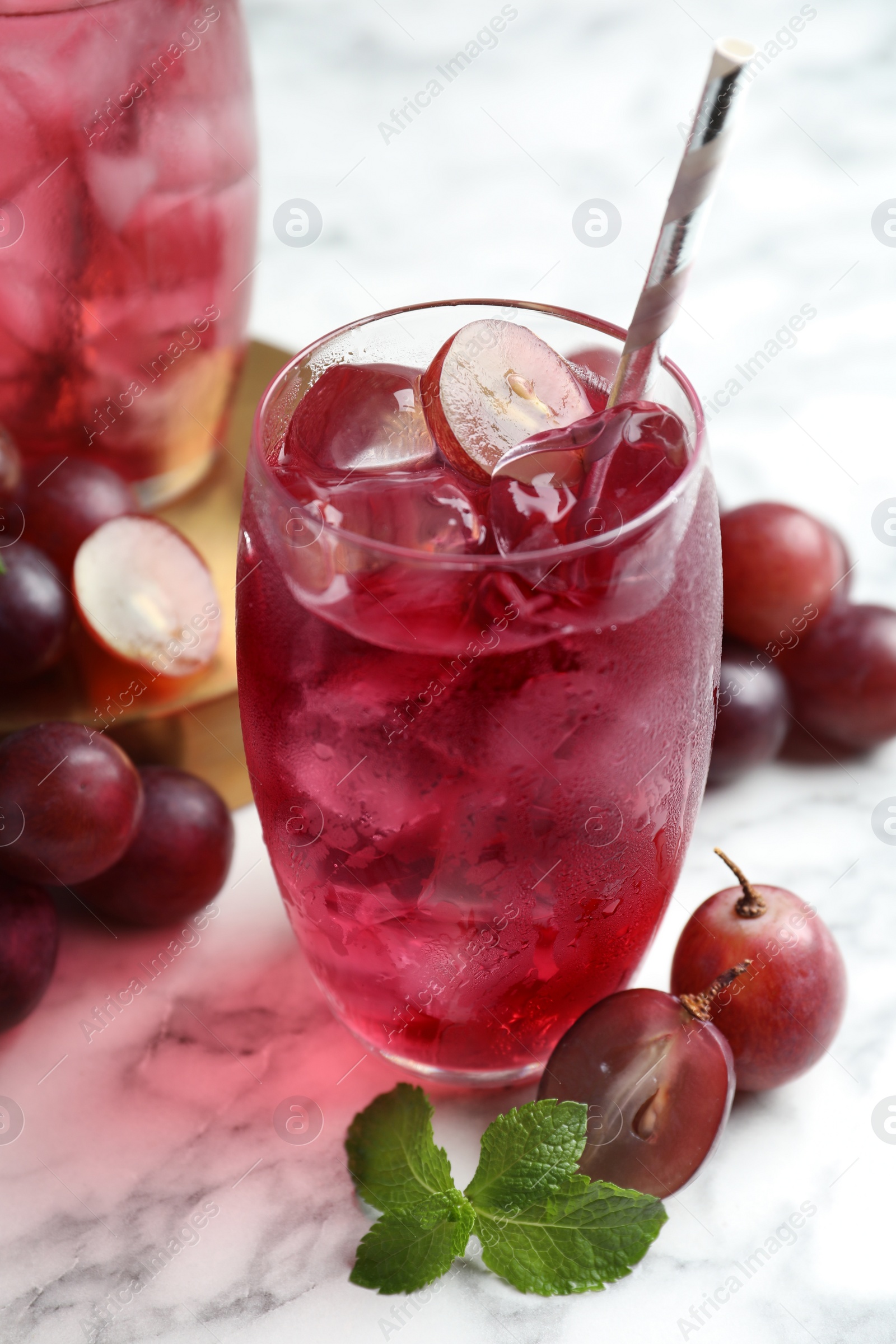 Photo of Delicious grape soda water with mint and berries on white marble table. Refreshing drink