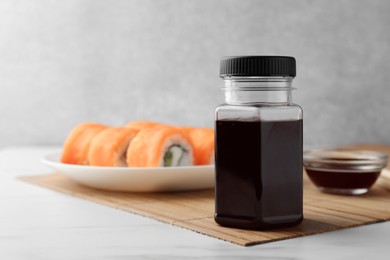 Photo of Tasty soy sauce and sushi rolls with salmon on light grey table. Space for text