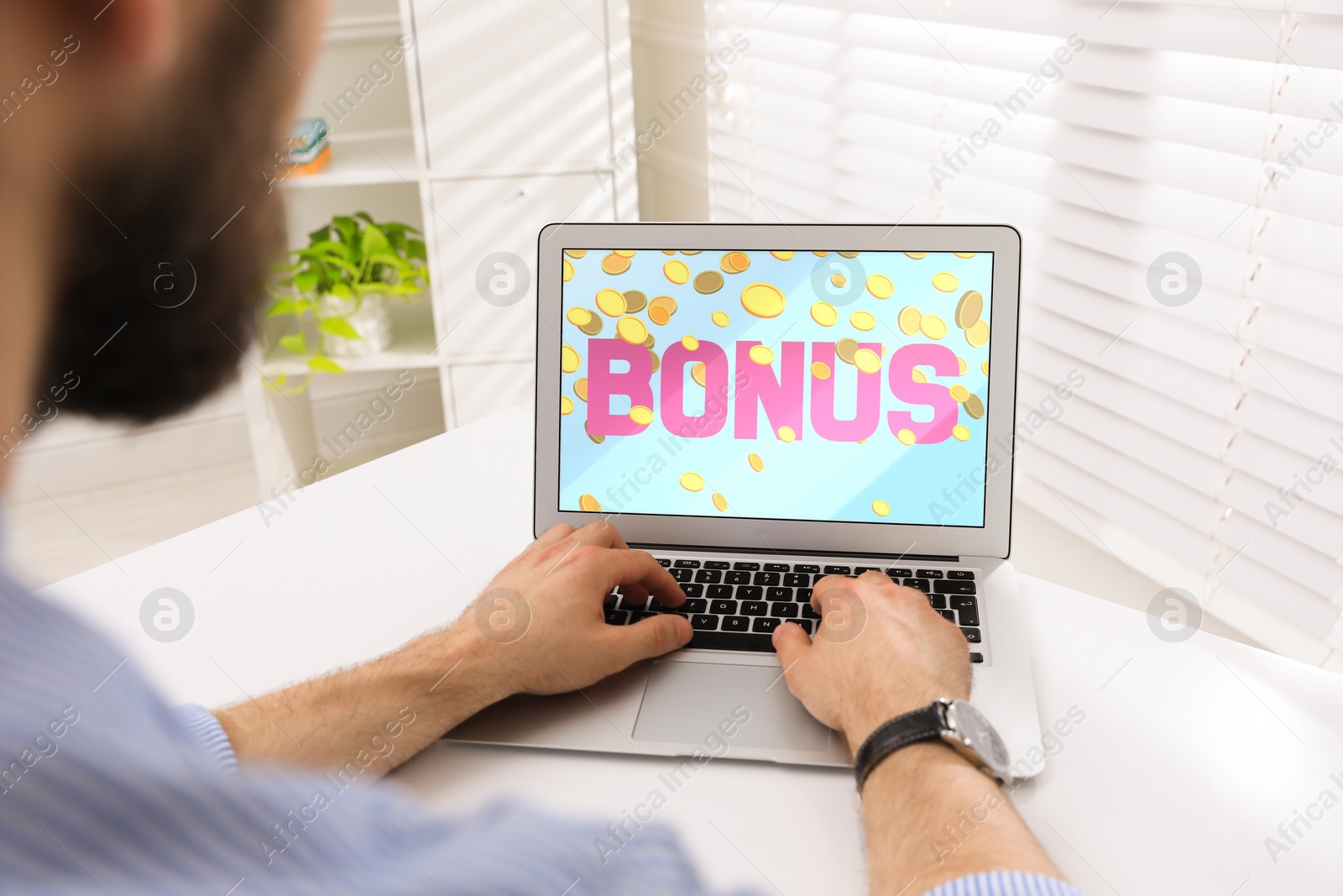 Image of Bonus gaining. Man using laptop at white table indoors, closeup. Illustration of falling coins and word on device screen