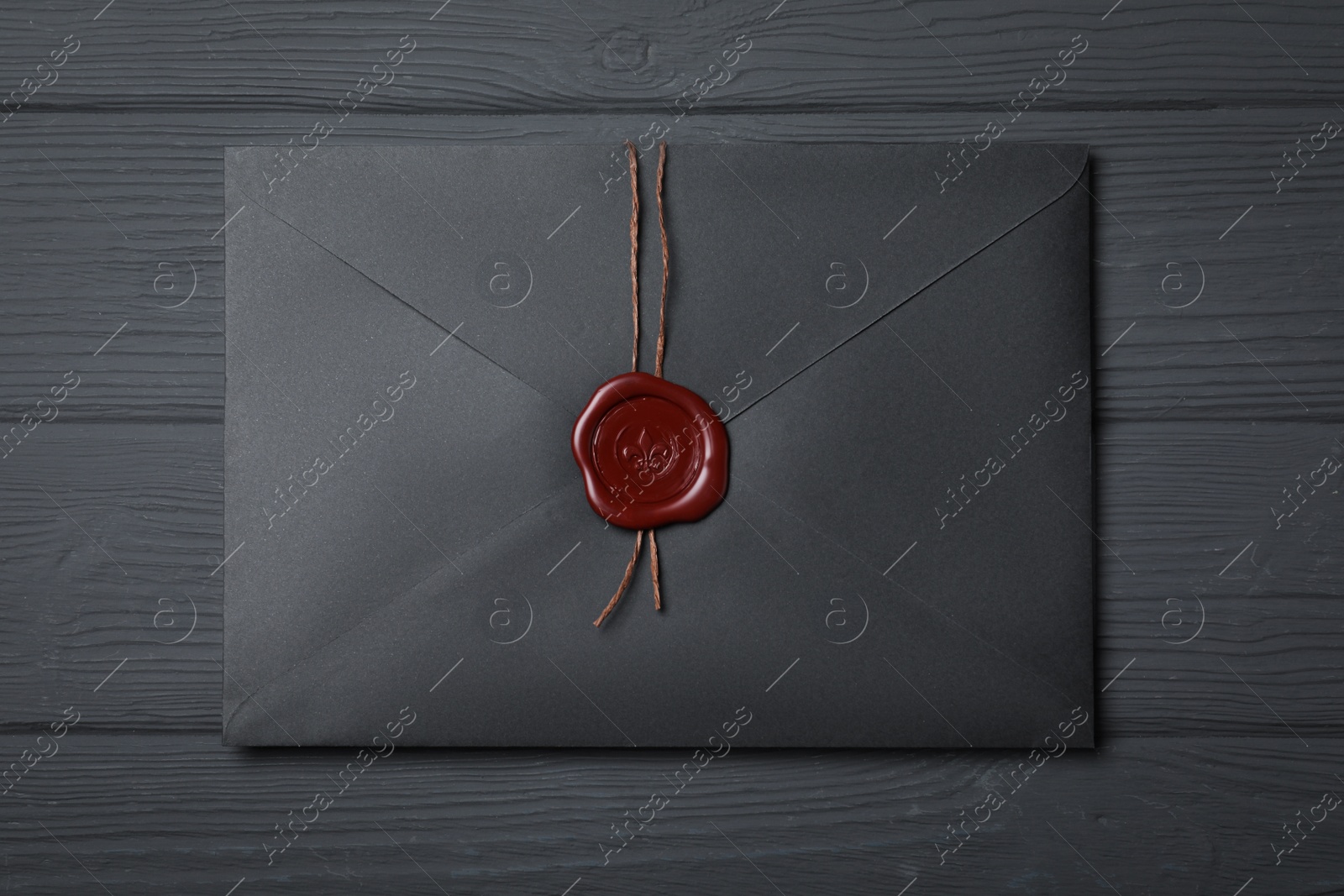 Photo of Envelope with wax seal on black wooden background, top view