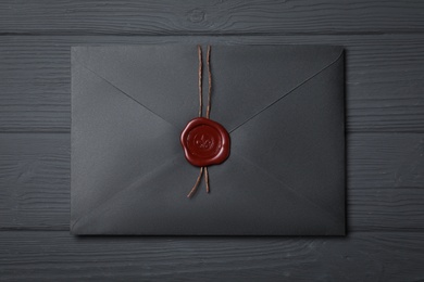 Photo of Envelope with wax seal on black wooden background, top view