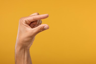 Photo of Man holding something in hand on orange background, closeup. Space for text