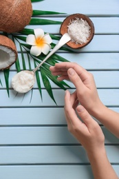 Photo of Young woman applying coconut oil on wooden background, closeup