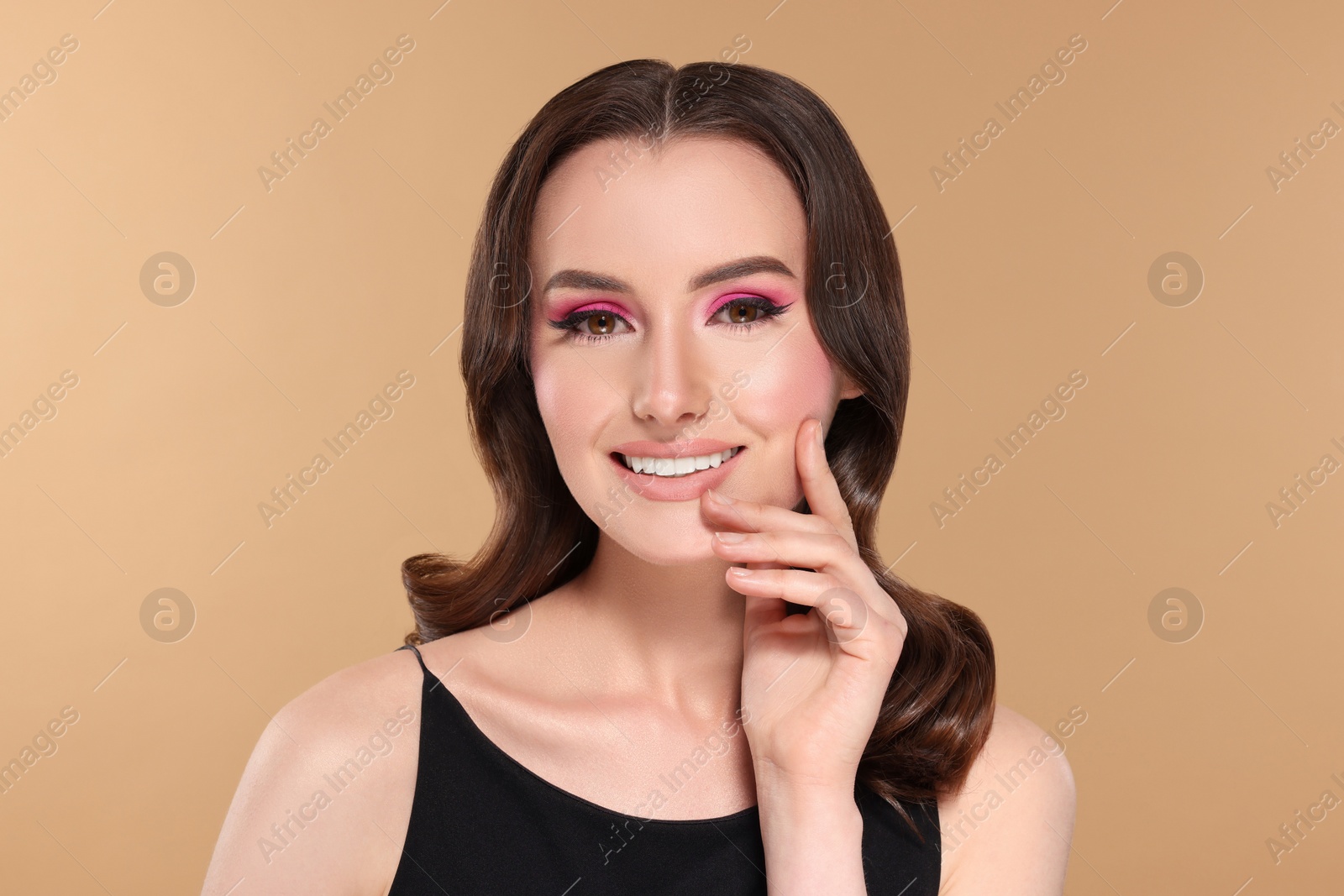 Photo of Portrait of beautiful young woman with makeup and gorgeous hair styling on beige background