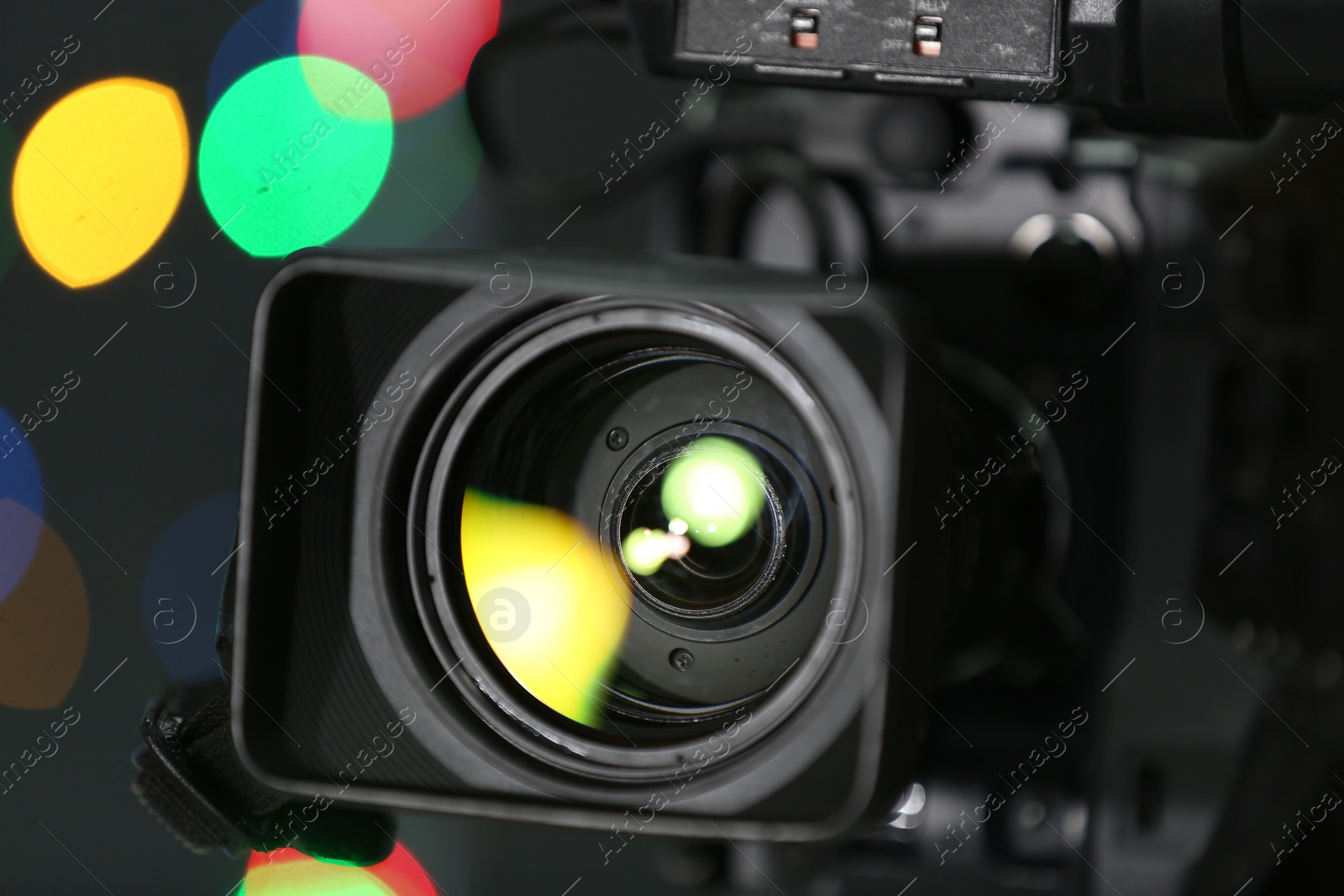 Photo of Modern video camera against blurred colorful lights, closeup