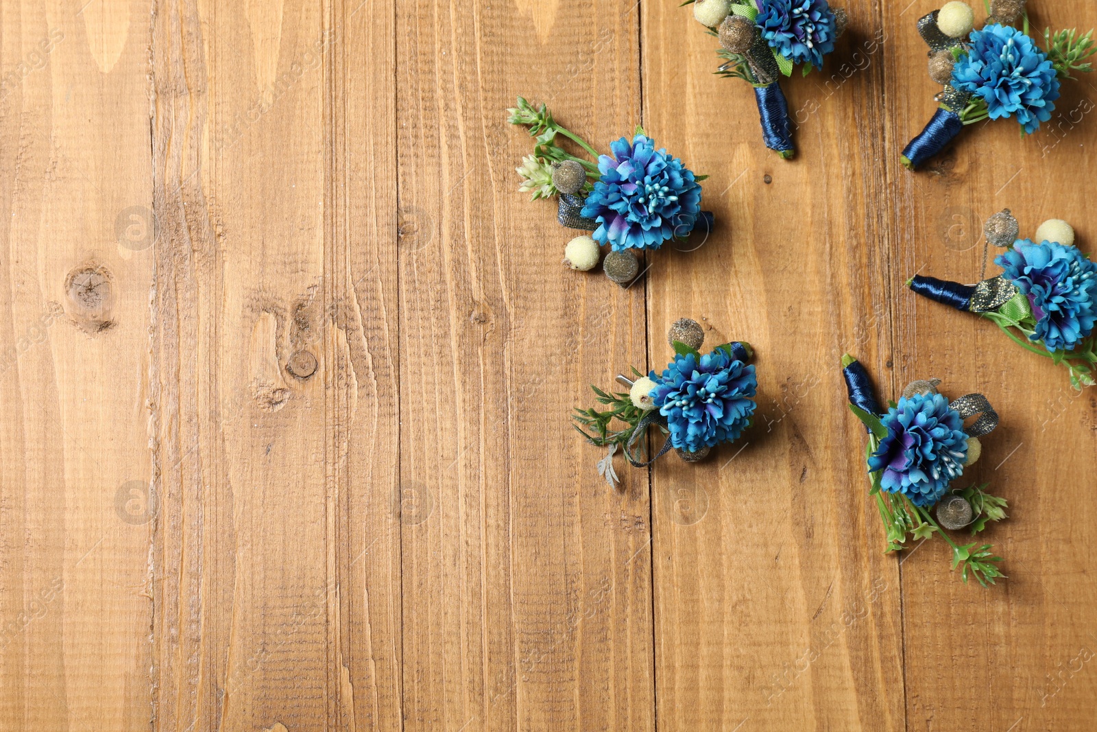 Photo of Stylish blue boutonnieres on wooden table, flat lay. Space for text