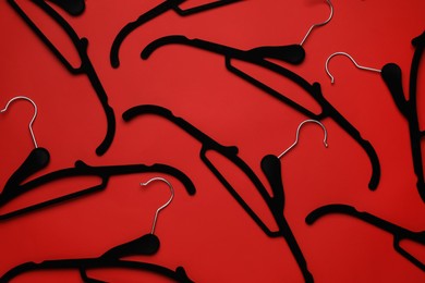 Photo of Empty clothes hangers on red background, flat lay