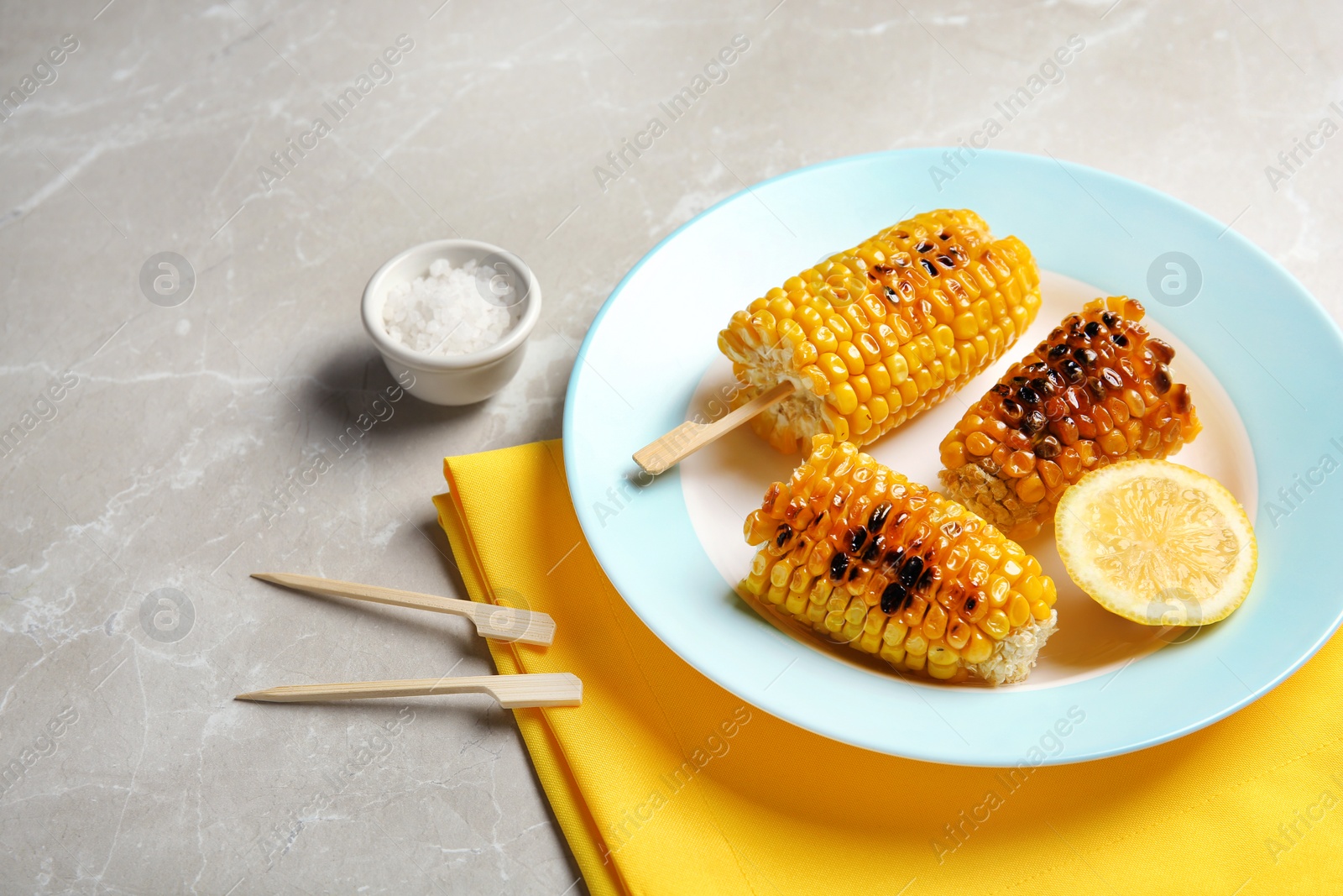 Photo of Plate with delicious grilled corn cobs on light table