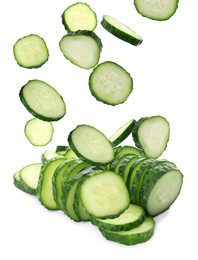 Slices of fresh green cucumbers falling on white background