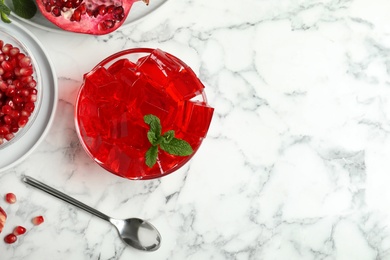 Flat lay composition with pomegranate jelly in bowl on marble table. Space for text