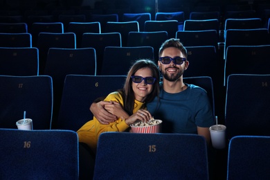 Young couple with popcorn watching movie in cinema theatre