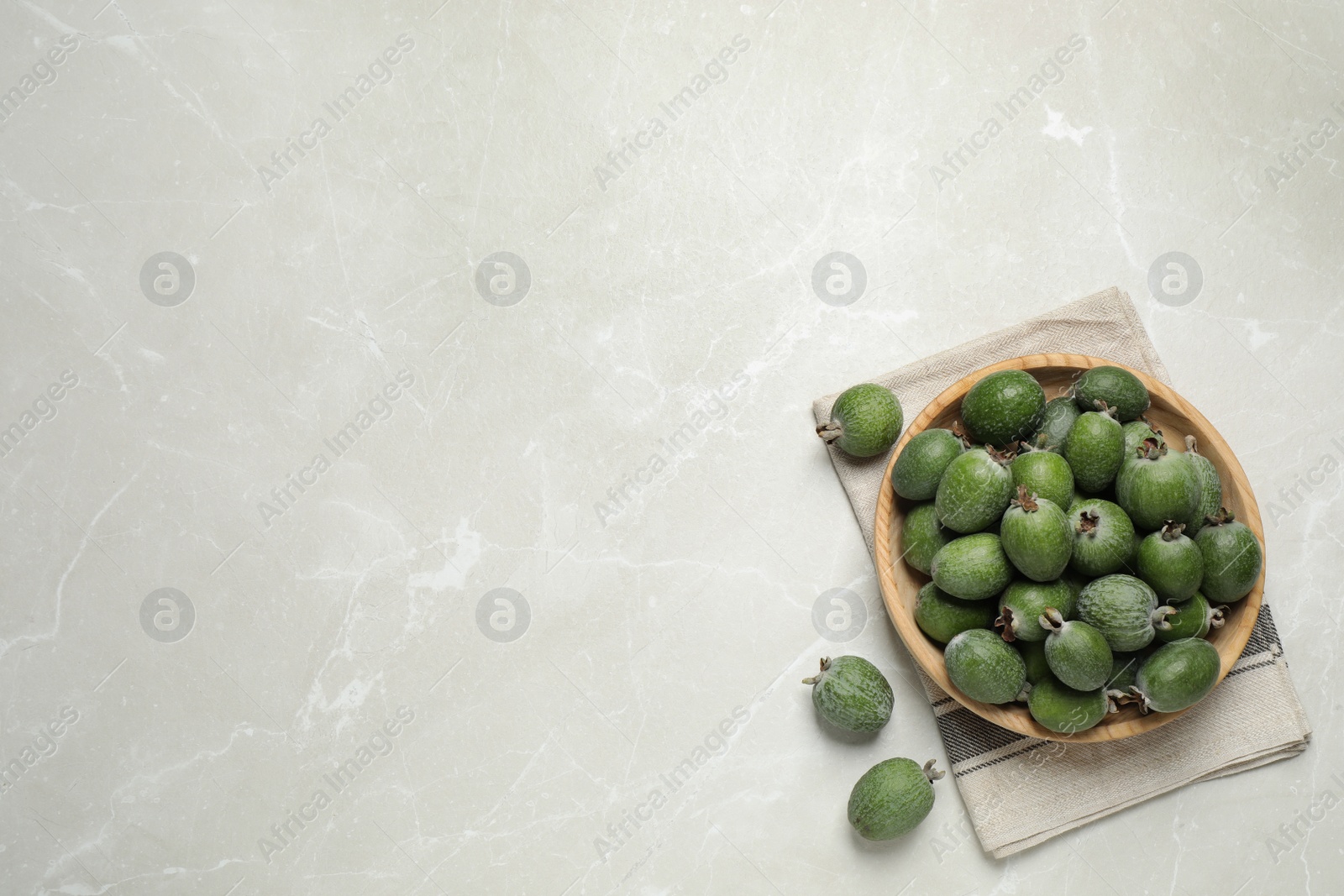 Photo of Flat lay composition with fresh green feijoa fruits on light grey marble table, space for text