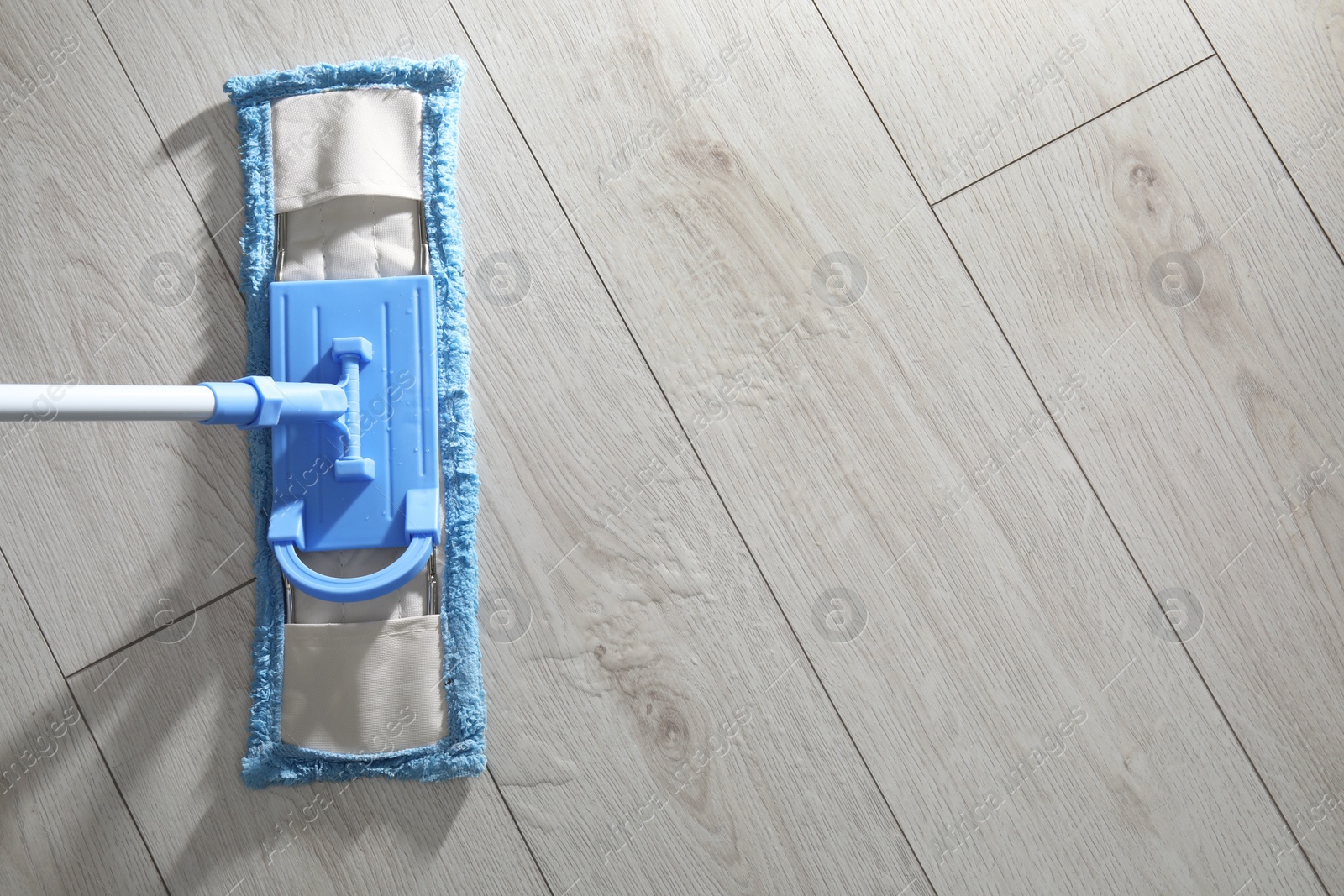 Photo of Cleaning white parquet floor with mop, top view. Space for text