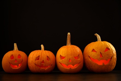 Photo of Spooky Jack pumpkin head lanterns on grey table against black background, space for text. Halloween decoration